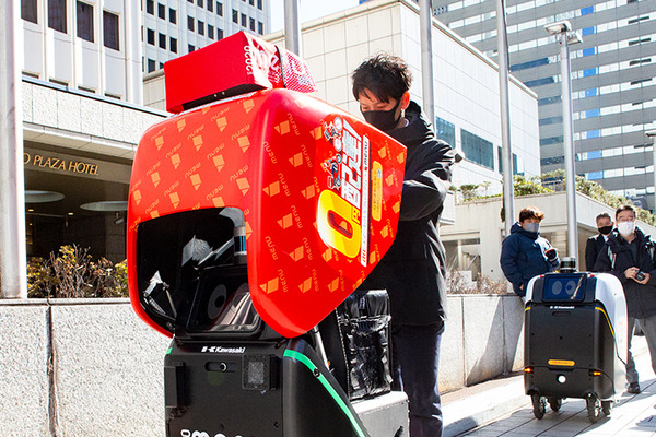 2台の5G自動配送ロボットが西新宿を快走！フードデリバリーと医薬品配送の自動化をめざす　川崎重工/KDDI/タケダ等6社が共同で