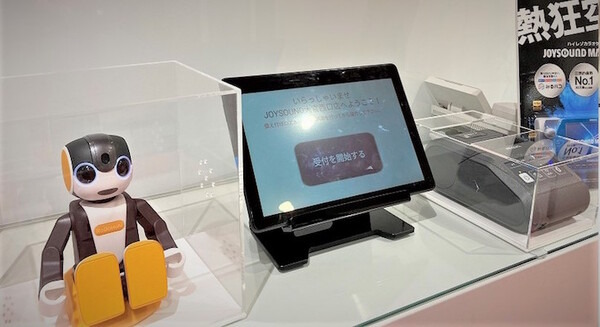 会話ロボット「ロボホン」がJOYSOUNDの受付業務をサポート 3店舗で実証実験後、全国の直営店で本格稼働を目指す 画像